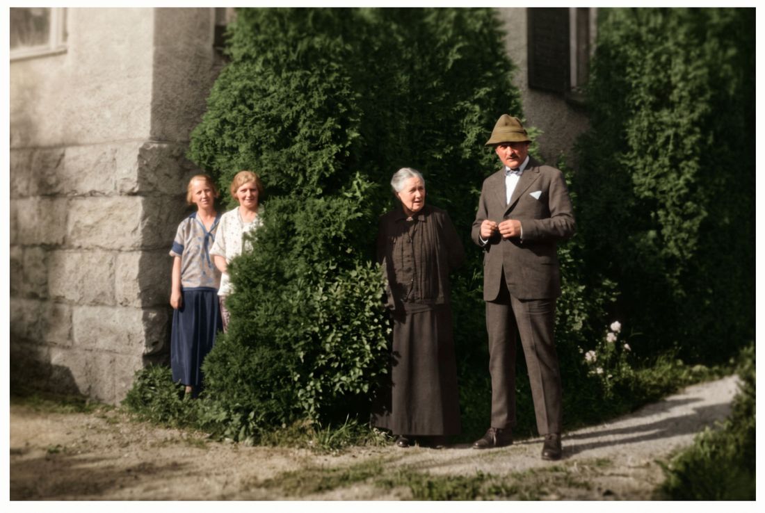 A family standing in front of a stone house, 1920s